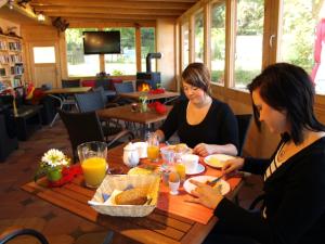 zwei Frauen sitzen an einem Tisch und essen Essen in der Unterkunft Ferienhaus am Luckower See in Sternberg