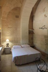 1 dormitorio con 1 cama en una pared de piedra en B&B Antico Aranceto, en Bagnolo del Salento
