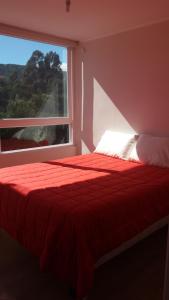 een slaapkamer met een rood bed en een raam bij Lomas 3 Bosque y Playa in Papudo