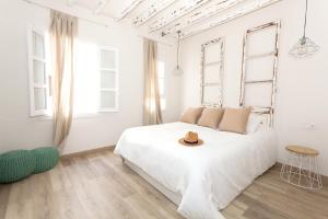 a white bedroom with a bed with a hat on it at Can Savella - Turismo de Interior in Palma de Mallorca