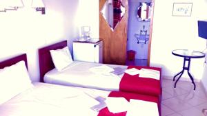 1 dormitorio con 2 camas con almohadas rojas y mesa en Kostis Rooms, en Korissia