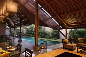 
a patio area with chairs, tables, and a pool at Ametis Villa in Canggu

