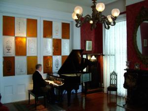 un hombre sentado en un piano en una habitación en Stone House Musical B&B, en Natchez
