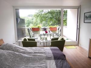 a bedroom with a bed and a balcony with a table and chairs at Apartment Harzgrün in Sankt Andreasberg