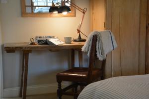 a room with a bed, chair, desk and a lamp at The Dolphin Inn in Thorpeness