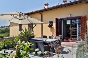 eine Terrasse mit einem Tisch und einem Sonnenschirm in der Unterkunft Luxury Villa in Grassina