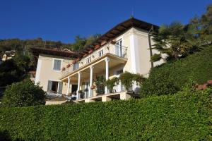 Großes weißes Haus mit Balkon auf einem Hügel in der Unterkunft Appartamento del Sole in Maccagno Superiore