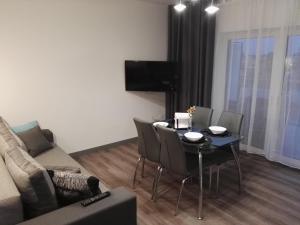 un salon avec une table, des chaises et un canapé dans l'établissement Apartament Nadmorski - Kompleks Pięć Mórz z basenem, à Sianożęty