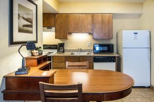 a kitchen with a table and a white refrigerator at Extended Studio Suites Hotel- Bossier City in Bossier City