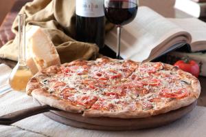a pizza sitting on a table next to a glass of wine at Dom Fedorovyh in Sergeyevka