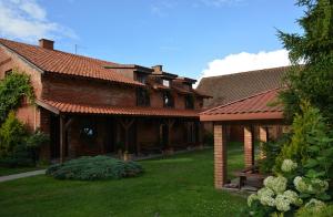 a brick house with a yard with grass and trees at Agro Przy Kominku in Rozogi