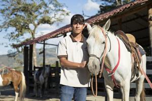 een man die naast een wit paard staat bij Hotel Hacienda El Rodeo in Rodeo