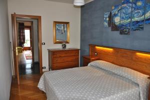 アオスタにあるAppartamento Ninoのベッドルーム1室(ベッド1台付)が備わります。壁には絵画が飾られています。