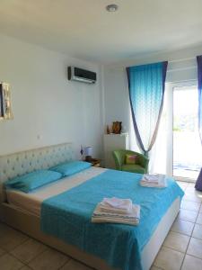 a bedroom with a bed with blue sheets and a window at Seaview near Athens & Sounio in Anavissos