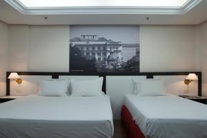 two beds in a room with a picture on the wall at Master Grande Hotel - Centro Histórico in Porto Alegre