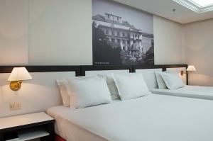 two beds with white pillows in a room at Master Grande Hotel - Centro Histórico in Porto Alegre