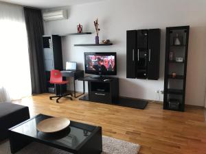 ein Wohnzimmer mit einem Flachbild-TV und einem Tisch in der Unterkunft NewTown Bucharest Apartment in Bukarest