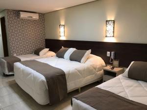 a hotel room with two beds and lights on the wall at Hotel do Reinildo II in Cachoeira Paulista