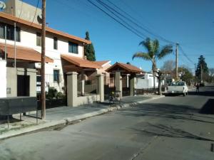 an empty street with a white car parked in front of a house at Complejo Camila in Villa Carlos Paz