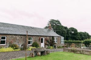 Incheoch Farm Cottage في Kilry: بيت حجري أمامه جلسة