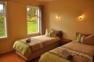 2 letti in una camera con 2 finestre di Relax a Lodge a Kerikeri Altre 37 foto