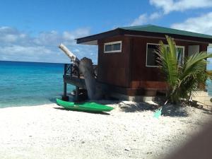 a house on a beach with a surfboard on the beach at Pension Turiroa " Chez Olga" in Avatoru