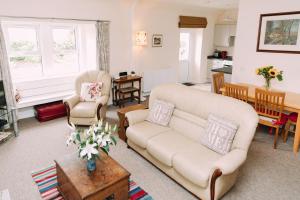 Incheoch Farm Cottage في Kilry: غرفة معيشة مع أريكة وكراسي وطاولة