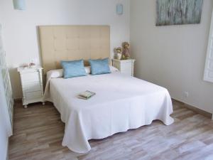 1 dormitorio con 1 cama blanca grande con almohadas azules en Casa Martina, en El Bosque