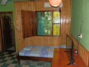 a bedroom with a bed, a desk and a window at Cabinas Casa Dolce Vita in Puerto Viejo