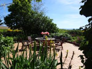 a patio with a table and chairs and flowers at Muddy Creek Cutting in Lauder