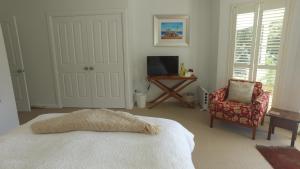 a bedroom with a bed and a chair and a television at The Ridge Retreat at Mollymook in Mollymook