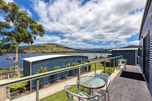 Port Huon Cottages في Port Huon: شرفة مع طاولة وكراسي وإطلالة على الماء