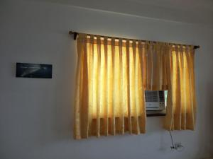 a window with a yellow curtain and a microwave at Anton's Beach Resort in Oslob