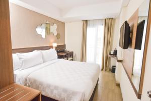 a hotel room with a white bed and a television at Golden Tulip Essential Tangerang in Tangerang