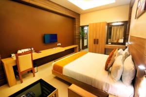 a bedroom with a bed and a desk with a computer at Imperial Heights in Deoghar