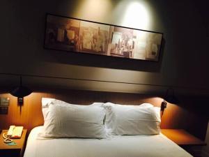 a bed with white pillows and a picture on the wall at Jinjiang Inn Select Shanghai International Tourist Resort Chuansha Subway Station in Shanghai