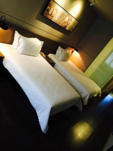 2 Betten in einem Hotelzimmer mit weißer Bettwäsche und Kissen in der Unterkunft Jinjiang Inn Select Shanghai International Tourist Resort Chuansha Subway Station in Shanghai
