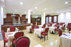 a restaurant with white tables and red chairs at Hotel Marconi in Bentivoglio