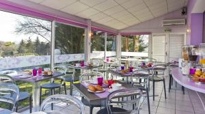 a restaurant with tables and chairs and windows at Tourhotel Blois in La Chaussée-Saint-Victor