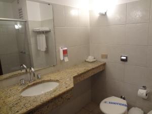 a bathroom with a sink and a toilet and a mirror at Camboa Hotel Paranaguá in Paranaguá
