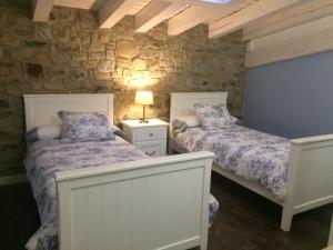 a bedroom with two beds and a stone wall at Casa Rural el Rincon de Maria in Villoslada de Cameros