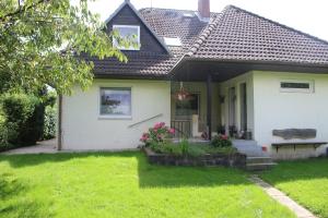 una pequeña casa blanca con porche y flores en Ferienwohnung-Familie-Baasch en Embsen