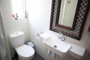 een badkamer met een toilet, een wastafel en een spiegel bij Aquarian Beachfront Apartment in Larnaka +12 foto's