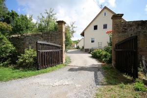 a gate to a stone wall and a house at Ferienwohnungen Lindleshof in Leinach