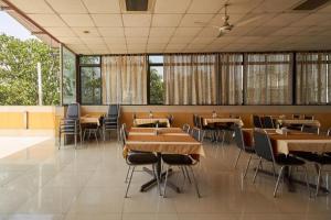 a dining room with tables and chairs and windows at Hotel Swan Inn in Pune