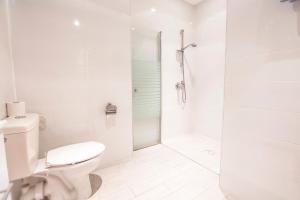 a white bathroom with a toilet and a shower at Central Laguardia Hotel in Tel Aviv