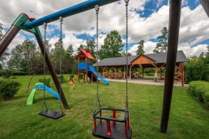 un parque infantil con tres columpios en un parque en Villa Bezycer, en Gowidlino