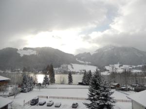 vista para um lago coberto de neve e montanhas em Hotel Garni Bernhard am See em Walchsee
