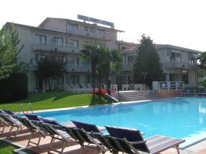 une grande piscine avec des chaises et un bâtiment dans l'établissement Hotel Porto Azzurro, à Sirmione