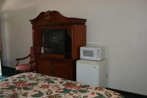 1 dormitorio con TV y microondas en HWY Express Inn and Suites, en Thatcher
